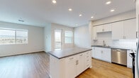 Located in San Ramon, CA, this well-designed 2-bedroom, 2-bathroom residence offers a functional single-floor layout with modern finishes throughout. The open-concept kitchen and living area serves as the heart of the home, featuring white shaker-style cabinetry, stone-look countertops, a subway tile backsplash, stainless steel appliances including a refrigerator with water dispenser, range, and microwave, plus a central island ideal for dining or prep work. Warm hardwood-style flooring flows throughout the space, complementing the clean, neutral palette of the walls and trim. The living area is bright and airy, with large windows that frame scenic hillside views and a glass door opening onto a private balcony. Both bedrooms are well-proportioned and filled with natural light from generous windows, each offering dedicated closet space with built-in wire shelving for organized storage. The primary bedroom includes direct access to both a walk-in closet and an en-suite bathroom. The bathrooms feature tub-shower combinations with tiled surrounds, stone-look vanity countertops, and wood-style flooring. A connecting hallway ties the layout together efficiently, and two full closets provide ample storage across the residence.