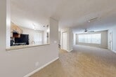 Located at 2801 NW 91st Ave in Coral Springs, Florida, this well-appointed one-bedroom, one-bathroom residence offers a comfortable and functional layout across a single floor. The open-concept living and dining area is generously sized, featuring plush wall-to-wall carpeting, a ceiling fan, and large windows dressed with vertical blinds that allow abundant natural light to fill the space. Pendant lighting above the dining area adds a warm, welcoming touch.

The kitchen is positioned adjacent to the living area and features a pass-through counter with a light stone surface, dark wood cabinetry, and a full suite of appliances, providing a practical and connected cooking space.

The carpeted bedroom is a comfortable retreat with a ceiling fan, large window with outdoor views, and access to multiple closets offering ample storage throughout the unit.

The bathroom is finished with wood-toned cabinetry, a stone-topped vanity, and hardwood flooring. A dedicated laundry room with a full-size washer and dryer is conveniently accessible from the bathroom area.

Additional highlights include a staircase with white railings and carpet treads, a private balcony, a utility room, and a hallway connecting the main areas. The textured ceilings and neutral color palette throughout give the space a clean, cohesive aesthetic.