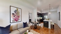 Located in the Galleria area of Houston, TX, this well-appointed one-bedroom, one-bathroom residence offers a thoughtfully designed single-floor layout. The living room is a bright, inviting space with warm hardwood flooring, a ceiling fan, and a bank of large windows that frame lush outdoor greenery, filling the room with natural light and a sense of openness.

The gourmet kitchen is a standout feature, showcasing rich dark-espresso cabinetry paired with stainless steel appliances, including a gas range, dishwasher, microwave, and French door refrigerator. A sleek white quartz island with pendant lighting above serves as both a prep space and casual gathering spot, while a classic subway tile backsplash adds a polished finishing touch. Hardwood floors extend throughout this area, lending warmth and continuity.

The bedroom is a comfortable retreat, highlighted by direct access to an outdoor balcony through floor-to-ceiling glass sliding doors, a ceiling fan, and soft carpeted flooring. The dedicated closet provides ample storage. The bathroom features a frameless glass walk-in shower, granite countertop vanity with ample cabinetry, and clean tile flooring. A hallway connects each space cohesively, completing this efficiently designed and well-finished home.