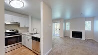 This efficiently designed 1-bedroom, 1-bathroom unit offers a functional and comfortable layout across a single floor. The open-concept kitchen and living area serves as the heart of the home, where the kitchen features crisp white shaker-style cabinetry, light-toned countertops, stainless steel appliances including a refrigerator, electric range, and dishwasher, and a peninsula that connects seamlessly to the living space. The kitchen is finished with warm hardwood-style flooring, while the living room transitions to plush wall-to-wall carpet. A standout feature of the living room is the classic fireplace framed by a clean white surround, complemented by multiple windows and a sliding glass door that opens to a private balcony with views of surrounding greenery, filling the space with natural light. The bedroom is a comfortable, carpeted retreat offering a sliding-door closet with a built-in rod and shelving, as well as a window with natural light. The full bathroom includes a combination tub and shower, a single vanity with a sink and mirror, and hardwood-style flooring. Throughout the unit, neutral tones and clean finishes contribute to a bright, move-in-ready ambiance.