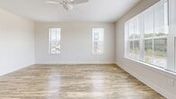 Located in Knightdale, NC, this well-appointed one-bedroom, one-bathroom residence offers a thoughtfully designed single-floor layout that maximizes both comfort and functionality. The open-concept kitchen and living area serves as the heart of the home, bathed in natural light from large windows fitted with blinds. The kitchen is a standout feature, showcasing an oversized granite-topped island with an undermount sink, sleek gray shaker-style cabinetry, a white tile backsplash, pendant lighting, and a full suite of stainless steel appliances including a refrigerator with ice maker, range, and built-in microwave. Wood-look luxury vinyl plank flooring runs throughout the main living areas, complementing the neutral, warm-toned walls. The living room benefits from multiple windows offering outdoor views and is equipped with a ceiling fan. The bedroom is a generously sized, carpeted retreat with its own window, providing a calm and private atmosphere. It connects to a walk-in closet outfitted with wire shelving on multiple walls, offering ample storage. The bathroom features a glass-enclosed walk-in shower with white tile surround and brushed nickel fixtures. Clean white trim and modern finishes throughout lend the space a crisp, contemporary aesthetic.