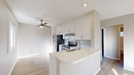This single-floor, 2-bedroom, 1-bathroom residence in Martinez, CA (94553) offers a clean, modern aesthetic throughout. The open-concept kitchen is a standout feature, showcasing white shaker cabinetry, light quartz countertops, a peninsula with a built-in sink, and stainless steel appliances including a refrigerator and electric range with hood ventilation. Light wood-look flooring runs through the kitchen and living areas, complementing the neutral wall tones and creating a bright, cohesive feel. The living area benefits from a ceiling fan and a large picture window that invites natural light and neighborhood views. Both bedrooms are comfortably proportioned with wood-look flooring, textured ceilings, and windows that bring in natural light. One bedroom features dual sliding-door closets, offering generous storage. The full bathroom is finished with a white vanity with quartz countertop, a tub-shower combination, wood-look tile flooring, and a frosted window for natural ventilation. A wall-mounted HVAC unit provides climate control in the living area. The overall ambiance is clean, bright, and move-in ready, offering a practical and comfortable living environment.