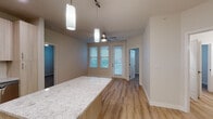 This single-floor residence showcases a thoughtfully designed open-concept layout that seamlessly connects the kitchen, dining, and living areas. The kitchen is well-appointed with light wood cabinetry, granite countertops, a full suite of stainless steel appliances including a refrigerator, range, microwave, and dishwasher, complemented by a peninsula that provides additional workspace and casual seating. Pendant lighting and recessed fixtures illuminate the space effectively. Wood-look plank flooring runs throughout the main living areas, adding warmth and continuity.

The living and dining area benefits from multiple windows with blinds, allowing natural light to filter in, while a ceiling fan promotes airflow. Large windows provide outdoor views and connect the interior to its surroundings.

Two carpeted bedrooms each feature ceiling fans and windows with outdoor views, creating comfortable, well-lit retreats. The primary bathroom includes a walk-in shower with chrome-framed glass doors and a granite-topped vanity with light wood cabinetry. A second full bathroom offers a combined tub and shower, matching granite vanity, and the same warm wood-look flooring found throughout the unit. The neutral color palette throughout creates a clean, cohesive aesthetic.