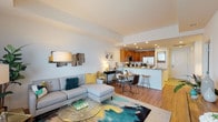 This single-floor residence is thoughtfully designed with a seamless open-concept layout that connects the living, dining, and kitchen areas into one cohesive, well-lit space. The living room is generously proportioned, featuring hardwood-style flooring, large windows with sheer curtains that invite abundant natural light, and access to a private balcony. Recessed lighting throughout enhances the bright, airy atmosphere.

The kitchen is equipped with warm-toned wood cabinetry, granite countertops, stainless steel appliances including a gas range, microwave, and refrigerator, and a peninsula with bar seating that doubles as a casual dining area. The granite counters and tile flooring add a polished, durable finish to this functional space.

The primary bedroom is a serene retreat highlighted by a bold, marble-patterned feature wall that serves as a striking focal point, complemented by soft carpeting and ambient lighting. The secondary bedroom offers a quieter aesthetic with neutral tones, plush carpet, and a window providing natural light.

The bathroom is finished with granite countertops, warm wood vanity cabinetry, tile flooring, and a tub-shower combination with glass sliding doors. Overall, the residence presents a cohesive modern aesthetic throughout.