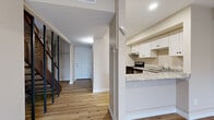 This two-story home in Kent, Ohio offers a thoughtfully laid-out floor plan across two levels, combining practical design with clean, modern finishes throughout. The main level features an open-concept kitchen and living area, where the kitchen stands out with white shaker-style cabinetry, granite countertops, stainless steel appliances, and ample counter space. The adjacent living room is bright and welcoming, highlighted by light hardwood-style flooring, a sliding glass door that opens to an outdoor patio, and baseboard heating. Exposed brick accents in the staircase area add a distinctive architectural character to the space. A dedicated laundry room with full-size washer and dryer hookups provides added convenience on the main level. Upstairs, two bedrooms offer comfortable retreats, each with hardwood-style flooring, baseboard heating, and natural light from well-placed windows. The spacious primary bedroom is particularly notable for its generous proportions. The full bathroom features a granite vanity, white cabinetry, and a tub-shower combination with a clean tile surround. Neutral tones and recessed lighting throughout the home create a bright, cohesive ambiance ideal for everyday living.