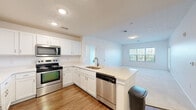 Located at 5000 Stein Drive in Cranberry Township, PA, this single-floor, three-bedroom, two-bathroom home offers a functional and well-appointed layout. The open-concept kitchen flows seamlessly into the living area, creating a bright, connected space ideal for everyday living. The kitchen is outfitted with white shaker-style cabinetry, light countertops, a peninsula with a sink, and a full suite of stainless steel appliances including a refrigerator, electric range with microwave, and dishwasher. Durable wood-look flooring runs throughout the kitchen, while plush carpeting extends across the living area and bedrooms. The living room benefits from a large multi-pane window and an exterior door, filling the space with natural light and offering views of the surrounding greenery. The primary bedroom is generously sized and includes a spacious walk-in closet with multi-tiered wire shelving. Two full bathrooms feature white vanities, tub-shower combinations, and wood-look flooring. The two additional bedrooms are bright and neutrally finished with carpeted floors. A hallway connects the bedrooms and bathrooms, with two closets providing ample additional storage throughout the home.
