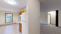 Located at 2653 Rice Creek Rd in New Brighton, MN, this 2-bedroom, 1-bathroom unit offers a practical and comfortable single-floor layout. The galley-style kitchen is efficiently designed with warm oak cabinetry lining both walls, white appliances including an electric range and refrigerator, a stainless steel sink, light countertops, and tile flooring — providing ample storage and workspace. The kitchen opens toward the main living area, which is carpeted and bathed in natural light from a sliding glass door that leads to a private balcony. A wall-mounted air conditioning unit serves the living space, and a baseboard heating system runs throughout the home. Both bedrooms are carpeted and feature neutral cream-toned walls. The primary bedroom includes a large sliding-door closet with rich wood-paneled doors, offering generous storage. A second closet provides additional organization. The full bathroom is finished with white tile flooring, a tub-shower combination with tile surround, a toilet, and a vanity with a granite-patterned countertop. Textured ceilings are consistent throughout the unit. The overall ambiance is clean, neutral, and functional, making it a comfortable and move-in ready home.