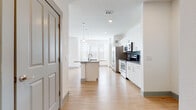 This single-floor residence features a clean, contemporary design throughout, with light hardwood-style flooring connecting the main living and kitchen areas. The open-concept kitchen is well-appointed with stainless steel appliances, including a side-by-side refrigerator, electric range, and over-the-range microwave. White shaker-style cabinetry with brushed nickel hardware lines the walls, complemented by gray subway tile backsplash and neutral countertops. A central island with a sink and pendant lighting above adds both function and visual interest, while windows at the far end allow natural light to fill the space.

The bedrooms feature plush carpeting and ceiling fans, with generous window coverage providing outdoor views and ample daylight. One bedroom includes access to a spacious walk-in closet outfitted with dual hanging rods, built-in shelving, and carpeted flooring for additional comfort.

Two full bathrooms are finished consistently, each offering white subway tile tub surrounds, hardwood-style flooring, white vanity cabinetry with gray countertops, and large framed mirrors. The primary bath features a double-sink vanity. A dedicated laundry area houses a full-size washer and dryer with overhead shelving for storage.