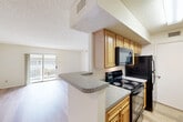 Located at 940 Quaker Ln in Warwick, Rhode Island, this single-story, 3-bedroom, 2-bathroom residence offers a practical and comfortable layout with consistent finishes throughout. Light wood laminate flooring flows across the main living areas and bedrooms, complemented by neutral white walls and textured ceilings.

The galley-style kitchen is well-appointed with warm honey-toned wood cabinetry, granite-look countertops, and black appliances including a range, built-in microwave, and refrigerator. A double-basin stainless steel sink sits opposite the range, and the kitchen opens toward the living area, enhancing the sense of connectivity.

The living room is bright and welcoming, featuring a sliding glass door that opens onto a white-railed balcony with pleasant views of the surrounding green lawn and mature trees. The three bedrooms are clean and simply finished, with the spacious primary bedroom offering a generous footprint. The two remaining bedrooms include window access for natural light.

Both bathrooms are equipped with tub-shower combinations featuring white tile surrounds, wood cabinetry, and granite-look countertops. One bathroom includes accessibility grab bars. A dedicated closet provides additional storage. The property's landscaped exterior adds to the overall appeal of this well-maintained Warwick residence.