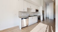 This contemporary 470 square foot studio apartment in Carson, CA, offers a harmonious blend of style and functionality. The space is characterized by its open floor plan, creating a seamless flow between living areas. The heart of the apartment is the state-of-the-art kitchen, featuring pristine white cabinetry, stainless steel appliances, and a subway tile backsplash. The kitchen's linear design maximizes efficiency while maintaining a sleek aesthetic.

Throughout the apartment, light wood flooring adds warmth and complements the crisp white walls, enhancing the sense of spaciousness. High ceilings and large windows allow natural light to flood the interior, creating a bright and airy ambiance. A ceiling fan provides both illumination and air circulation.

The living area is versatile, easily accommodating various furniture arrangements to suit the resident's needs. The bedroom space, while open to the main living area, can be defined through strategic furniture placement. Built-in closets offer ample storage solutions.

This studio apartment exemplifies modern urban living, with its clean lines, neutral color palette, and thoughtful design elements that maximize the use of space in a compact yet comfortable environment.