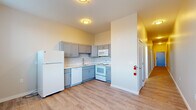 Located at 366 W Allen St in Allentown, Pennsylvania, this 2-bedroom, 1-bathroom unit offers a practical and well-organized single-floor layout. Light wood-style luxury vinyl flooring runs consistently throughout the space, contributing to a clean, cohesive aesthetic. The kitchen is equipped with gray shaker-style cabinetry, white appliances including a refrigerator, electric range, built-in microwave, and dishwasher, as well as a double-basin sink — all arranged in an efficient L-shaped configuration. A long, well-lit hallway connects the kitchen area to the private living quarters, with flush-mount ceiling lighting and a small wall-mounted utility panel along the corridor. The two bedrooms are bright and modestly sized, with the primary bedroom offering a large window that frames outdoor views and allows ample natural light. Both bedrooms are serviced by dedicated closets, providing practical storage solutions. The bathroom features a full-sized soaking tub with an integrated shower surround in crisp white, complemented by neutral-toned walls and wood-style flooring. A baseboard heating unit is visible in one of the bedrooms, ensuring year-round comfort. The overall ambiance is clean, understated, and move-in ready.