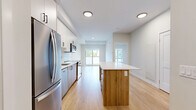 Located at 7219 Sharon Ave in Niagara Falls, Ontario, this thoughtfully designed one-bedroom, one-bathroom unit offers a efficient and modern living layout across a single floor. Light hardwood flooring flows consistently throughout the main living areas, creating a warm and cohesive aesthetic.

The kitchen is a standout feature, finished with a clean combination of white upper cabinetry and natural wood-toned lower cabinets, complemented by a classic subway tile backsplash. Stainless steel appliances — including a French door refrigerator, range, microwave, and dishwasher — add a polished, contemporary touch. A kitchen island with a light stone countertop provides additional prep space and a casual dining option.

The bedroom is a calm, neutral retreat bathed in natural light from a large window that frames views of the surrounding neighbourhood's rooftops and greenery. Crisp white walls and light flooring contribute to a bright, airy feel.

The bathroom is finished with large-format tile flooring, a natural wood vanity with a white quartz countertop, a framed mirror, and a sleek black hardware finish. A dedicated closet provides practical storage. The unit's clean lines, neutral palette, and modern finishes make it an efficiently designed and inviting space.