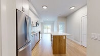 Located at 7219 Sharon Ave in Niagara Falls, Ontario, this thoughtfully designed one-bedroom, one-bathroom unit offers a efficient and modern living layout across a single floor. Light hardwood flooring flows consistently throughout the main living areas, creating a warm and cohesive aesthetic.

The kitchen is a standout feature, finished with a clean combination of white upper cabinetry and natural wood-toned lower cabinets, complemented by a classic subway tile backsplash. Stainless steel appliances — including a French door refrigerator, range, microwave, and dishwasher — add a polished, contemporary touch. A kitchen island with a light stone countertop provides additional prep space and a casual dining option.

The bedroom is a calm, neutral retreat bathed in natural light from a large window that frames views of the surrounding neighbourhood's rooftops and greenery. Crisp white walls and light flooring contribute to a bright, airy feel.

The bathroom is finished with large-format tile flooring, a natural wood vanity with a white quartz countertop, a framed mirror, and a sleek black hardware finish. A dedicated closet provides practical storage. The unit's clean lines, neutral palette, and modern finishes make it an efficiently designed and inviting space.
