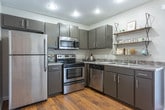 Located at 621 Memorial Dr in Red Bank, Tennessee, this two-story home offers a well-planned layout with functional living spaces across both floors. Rich hardwood flooring flows throughout, lending warmth and continuity to the interior.

The main level opens into a comfortable living room featuring a bold teal accent wall, natural light from a large front window, and a staircase with a wood-railed banister leading to the upper floor. Adjacent to the living area is a dedicated dining nook with vertical blinds that filter in natural light. The kitchen is thoughtfully equipped with dark gray cabinetry, granite-style countertops, stainless steel appliances including a refrigerator, range, microwave, and dishwasher, and open floating shelving for additional storage. A half bathroom on the main level features a vanity with dark cabinetry and warm hardwood flooring.

Upstairs, two well-proportioned bedrooms each include ceiling fans, natural light from windows with sheer curtains, and continued hardwood flooring. A full bathroom on this level offers a wide vanity with a white countertop and a large mirror. The overhead model view confirms a practical, symmetrical upper floor configuration. Overall, the home presents a clean, modern aesthetic with consistent finishes throughout.