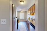 Located at 18242 Middlebelt Rd in Livonia, Michigan, this one-bedroom, one-bathroom residence offers a well-organized single-floor layout designed for comfortable everyday living. The galley-style kitchen is a functional highlight, featuring warm wood cabinetry, granite-style countertops, a stainless steel refrigerator, a black range with an over-the-range microwave, and a built-in dishwasher. Rich hardwood-style flooring runs throughout the kitchen and connects seamlessly to the main living areas, while a ceiling fan provides additional comfort. The living room is bright and open, benefiting from a large window dressed with slatted blinds that allow ample natural light to filter in. The bedroom is a comfortable, carpeted space with a dedicated window offering outdoor views, creating a calm and restful atmosphere. Two closets provide practical storage solutions throughout the unit. The bathroom is well-appointed with a warm wood vanity, granite-style countertop, a single sink, and a shower-tub combination, complemented by hardwood-style flooring and a window for natural light. Three hallway areas connect the spaces efficiently, contributing to the overall flow of the layout. Neutral wall tones and consistent finishes throughout lend the space a cohesive, move-in-ready appeal.