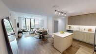 This thoughtfully designed 2-bedroom, 3-bathroom residence offers a clean, contemporary aesthetic across a single floor. The open-concept kitchen and living area serves as the heart of the home, featuring light wood cabinetry, stainless steel appliances including a French door refrigerator, a built-in wine cooler, and a central island with seating — ideal for both everyday living and entertaining. Track lighting and wood-look flooring throughout the kitchen lend a polished, modern feel.

The living room is bright and airy, anchored by floor-to-ceiling sliding glass doors that open to a private balcony overlooking a lush, resort-style courtyard with a sparkling pool and tropical landscaping. The space invites natural light while offering scenic outdoor views.

The primary bedroom is generously sized and includes a ceiling fan, direct access to a private en-suite bathroom, and a walk-in closet. The en-suite features a dual-sink vanity with backlit mirrors and stone countertops. A second bedroom offers large windows with courtyard views and plush carpeting. The bathrooms are finished in crisp white tile with soaking tub and shower combinations. Two dedicated closets provide ample storage throughout the residence.