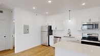 Located at Vista On The Park in Wright City, Missouri, this single-story, one-bedroom, one-bathroom residence offers a clean, contemporary design characterized by crisp white walls, light hardwood-style flooring, and an open, airy layout throughout.

The kitchen is a standout feature, equipped with stainless steel appliances including a full-size refrigerator, electric range, built-in microwave, and dishwasher. White shaker-style cabinetry with matte black hardware pairs with light quartz countertops and a peninsula island, providing generous prep and storage space. A stylish pendant light accents the sink area, which features a matte black gooseneck faucet.

The living area is well-proportioned and bright, benefiting from natural light through a window overlooking the outdoors. A ceiling fan is installed overhead, and a distinctive sliding barn door adds a modern-rustic accent while connecting to the kitchen area.

The bedroom is comfortably sized with additional natural light, a ceiling fan, and direct access to the bathroom. The bathroom includes a full tub-shower combination with clean white surround finishes.

A dedicated laundry area houses a full-size top-loading washer and dryer, adding everyday convenience. The overall aesthetic is modern and move-in ready, with consistent finishes carried throughout the space.