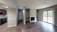 This single-story residence offers a thoughtfully designed layout with a cohesive neutral color palette and durable wood-look flooring running through the main living areas. The spacious living room serves as the centerpiece of the home, highlighted by a classic fireplace flanked by built-in shelving units on either side — an ideal combination of style and functionality. A sliding glass door connects the living area directly to a private balcony, filling the room with natural light and offering outdoor views.

The kitchen features rich dark cabinetry paired with granite-look countertops, providing ample prep and storage space. A hallway fitted with a wall sconce light leads to the private quarters, where bedrooms are finished with plush carpeting and windows dressed with blinds for natural light and privacy.

The bathroom is well-equipped with a dark vanity cabinet topped with granite countertops, an undermount sink, and a tiled shower-tub combination. Throughout the residence, textured ceilings, clean white trim, and consistent finishes contribute to a polished, move-in-ready atmosphere that balances comfort with practical living.