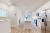 Located at 6002 Prosperity Commons Rd in Charlotte, NC, this four-story home offers four bedrooms and five bathrooms across a well-organized, multi-level layout. The ground floor houses an attached garage with concrete flooring and drywall-finished walls, alongside an entrance that leads to the staircase connecting all levels.

The main living floor features a bright, open-concept kitchen and living area finished with light hardwood-style flooring throughout. The kitchen is equipped with white shaker cabinetry, light quartz countertops, a center island with an undermount sink, pendant lighting, and a full suite of stainless steel appliances including a refrigerator, range, microwave, and dishwasher. Natural light flows in through windows offering neighborhood views.

The upper floors distribute four bedrooms, each with light wood flooring, neutral walls, and windows with blinds providing natural light and street views. The primary bedroom includes a connected en-suite bathroom. Additional bathrooms are clean and modern, featuring gray cabinetry and ample vanity space. Closets and a hallway provide practical storage and circulation throughout.

The uppermost floor offers a more intimate footprint, ideal for a private bedroom or flex space. Staircases connecting each level are finished with wood treads and white risers, accented by black hardware details consistent with the home's modern aesthetic.