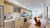 Located at 5050 Arrow Hwy in Montclair, CA, this well-appointed one-bedroom, one-bathroom residence offers a thoughtfully designed single-floor layout that maximizes every square foot. The open-concept kitchen, dining, and living area serves as the heart of the home, featuring light wood cabinetry with matte black hardware, white quartz countertops, a herringbone tile backsplash, and a full suite of stainless steel appliances including a refrigerator, range, microwave, and dishwasher. Open shelving adds a modern touch to the kitchen's functional design. Light wood-look flooring flows throughout the main living area, enhancing the bright, airy ambiance. The living room opens directly to a private balcony through glass doors, allowing natural light to pour in. The bedroom is a serene retreat with plush carpeting, large windows with balcony access, and a tasteful accent wall. The bathroom features a clean, modern aesthetic with a wood-vanity, white countertop, and a glass-enclosed walk-in shower with white tile surround and built-in shelving. Additional conveniences include in-unit laundry and two closets, rounding out this efficient and stylish residence.