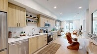 Located at 5050 Arrow Hwy in Montclair, CA, this well-appointed one-bedroom, one-bathroom residence offers a thoughtfully designed single-floor layout that maximizes every square foot. The open-concept kitchen, dining, and living area serves as the heart of the home, featuring light wood cabinetry with matte black hardware, white quartz countertops, a herringbone tile backsplash, and a full suite of stainless steel appliances including a refrigerator, range, microwave, and dishwasher. Open shelving adds a modern touch to the kitchen's functional design. Light wood-look flooring flows throughout the main living area, enhancing the bright, airy ambiance. The living room opens directly to a private balcony through glass doors, allowing natural light to pour in. The bedroom is a serene retreat with plush carpeting, large windows with balcony access, and a tasteful accent wall. The bathroom features a clean, modern aesthetic with a wood-vanity, white countertop, and a glass-enclosed walk-in shower with white tile surround and built-in shelving. Additional conveniences include in-unit laundry and two closets, rounding out this efficient and stylish residence.
