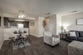 Located at 16950 Jasmine St in Victorville, California, this single-floor unit offers a well-organized, open-concept layout designed for comfortable everyday living. The main living area is spacious and inviting, featuring warm wood-style flooring, a ceiling fan, and a textured ceiling that extends throughout the common spaces. The living room flows naturally into the dining area, creating a cohesive entertaining space with room for both seating and a dining set.

The kitchen is functionally designed with rich dark cabinetry, white appliances including a gas range, over-the-range microwave, dishwasher, and refrigerator, complemented by light countertops and a double-basin sink. The layout maximizes efficiency and storage within a compact footprint.

The bedroom is a well-sized, carpeted retreat featuring a sliding glass door that leads to an outdoor area, allowing for natural light and exterior access. Vertical blinds provide privacy and light control.

The bathroom is neatly appointed with a tub-shower combination, wood-style flooring, a vanity with storage, and clean white tile surround. The warm, neutral color palette carried throughout the unit creates a cohesive and welcoming atmosphere, making this a practical and comfortable single-level residence in the high desert community of Victorville.