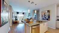 This single-floor residence offers a thoughtfully designed open-concept layout that seamlessly connects the kitchen, dining, and living areas. The kitchen is outfitted with white shaker cabinetry, granite countertops, a tile backsplash, and a full suite of stainless steel appliances, including a range, microwave, refrigerator, and dishwasher. A peninsula with pendant lighting provides additional workspace and casual seating. Wood-style flooring runs through the main living areas, enhancing the bright, contemporary feel.

The living room features a ceiling fan, neutral-toned walls, and a sliding glass door that opens to a private balcony with outdoor views. Multiple bedrooms are carpeted and well-lit by large windows, each with ceiling fans. The primary bedroom offers ample space and multiple windows for natural light. Bathrooms are finished with granite-topped white vanities and wood-style flooring; one includes a tub-shower combination, while another features an illuminated mirror above a single-sink vanity. The cohesive design throughout emphasizes modern, functional living.