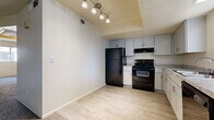 This single-floor, 2-bedroom, 1-bathroom residence offers a practical and comfortable layout designed to maximize every square foot of living space. The kitchen is a functional highlight, featuring white shaker-style cabinetry, granite-look countertops, light wood-look vinyl flooring, and black appliances including a refrigerator, electric range, and dishwasher. A track light fixture overhead adds a modern touch to the space.

The living room is bright and welcoming, with a large window fitted with vertical blinds that invite natural light while providing privacy. Neutral-toned carpet and light-colored walls create a clean, versatile backdrop throughout the living areas and bedrooms.

Both bedrooms are carpeted and offer comfortable proportions, each with windows that bring in natural light. The primary bedroom includes a dedicated closet with sliding doors and a built-in hanging rod, providing convenient storage. A hallway connects the main living areas to the bedrooms and bathroom, adding to the functional flow of the floor plan.

The bathroom is a standout space, showcasing a marble-style tiled tub and shower surround, wood-look tile flooring, a granite-topped vanity with a white shaker cabinet, and a mirrored medicine cabinet above the sink. The overall aesthetic is clean and contemporary, offering a cohesive and move-in-ready living environment.