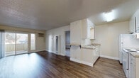 Located at 3777 Mowry Ave in Fremont, California, this single-floor residence offers a well-organized and functional layout designed for comfortable everyday living. The open living area is finished with durable wood-style flooring and neutral-toned walls, creating a clean and bright atmosphere. A ceiling fan adds comfort to the space, while a wall-mounted A/C unit provides climate control. Sliding glass doors lead to an outdoor area, allowing natural light to fill the room. The kitchen is efficiently designed with white cabinetry, granite-style countertops, a peninsula with a breakfast bar overhang, white appliances including a refrigerator and electric range, and a utility sink. A textured ceiling runs throughout the main living and kitchen areas, adding a classic residential character. The bedroom is carpeted for added warmth and comfort, featuring a large window with vertical blinds that invite natural light. The full bathroom is finished with the same wood-style flooring as the main living areas and includes a white vanity with storage, a toilet, and a tub-shower combination. Overall, the unit presents a straightforward, well-maintained interior with a cohesive neutral palette throughout.