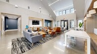 Located at 2 S Conifer Dr in Elizabethtown, PA, this thoughtfully designed community clubhouse offers a generous single-floor layout that seamlessly blends social and wellness amenities. The main living areas are anchored by soaring vaulted ceilings, white shiplap walls, and polished concrete floors that lend a clean, contemporary aesthetic. Large black-framed windows flood the space with natural light and provide views of the surrounding landscape. Two distinct living areas offer flexible gathering spaces — one features a sleek media wall with a mounted TV, a warm wood counter bar, and an eclectic mix of seating including plush sofas and cognac-toned lounge chairs. The other showcases intimate built-in banquette nooks with bold teal geometric wall accents, overhead sconce lighting, and white tables with powder-blue chairs, ideal for small group meetings or casual conversation. A dedicated fitness center occupies a substantial portion of the floor plan, divided into two well-equipped zones: a cardio area lined with treadmills, ellipticals, stair climbers, and rowers beneath vaulted ceilings with ceiling fans, and a strength training zone featuring a full dumbbell rack, weight benches, a cable machine, and mirrored walls accented by a bold blue stripe. Natural light and mounted TVs enhance the workout experience throughout.