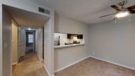 This single-story residence at River Oak Apartments offers a well-organized layout with neutral-toned walls and plush wall-to-wall carpeting throughout the main living areas and bedrooms. The living room is a comfortable, open space highlighted by a ceiling fan with integrated lighting and a sliding glass door that provides access to the outdoors and fills the room with natural light.

The kitchen is positioned behind a pass-through counter with light granite-style countertops, creating a convenient connection to the living area. Dark espresso cabinetry lines the kitchen walls, complemented by a stainless steel electric range with a ventilation hood above, offering a clean, functional workspace.

The bedrooms are generously sized, featuring soft carpeting, neutral walls, and ample natural light from multiple windows fitted with blinds. At least one bedroom includes a walk-in closet with built-in shelving, providing practical storage.

The bathroom features warm hardwood-style flooring, a dark wood vanity with a white countertop and single sink, a large mirror with overhead lighting, and a full tub-shower combination. The overall ambiance of the unit is clean, understated, and move-in ready.
