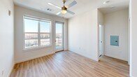 Located at 1803 S 46th St in Rogers, Arkansas, this well-appointed 2-bedroom, 2-bathroom unit offers a thoughtfully designed single-floor layout with a clean, contemporary aesthetic throughout. The open-concept kitchen and living area serves as the heart of the home, featuring a central island with a sink, crisp white quartz countertops, two-tone cabinetry in white and gray, subway tile backsplash, and a full suite of stainless steel appliances including a side-by-side refrigerator, range, and built-in microwave. Light hardwood-style flooring runs throughout the main living areas, complemented by recessed lighting. The primary bedroom offers balcony access through a glass door, large windows framing open views of the surrounding Rogers cityscape, a ceiling fan, and a walk-in closet with wire shelving. The second bedroom is carpeted and equally bright, with a large window and ceiling fan. Both bathrooms are finished with white subway tile — one featuring a glass-enclosed walk-in shower, the other a full soaking tub and shower combo — each paired with modern gray vanities and light wood flooring. The unit's elevated position allows for expansive outdoor views from multiple rooms, enhancing the overall sense of openness and natural light.