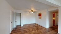 Located at 3501 Pimlico Pkwy in Lexington, Kentucky, this single-floor residence offers a well-organized layout with a variety of functional living spaces. The main living area features rich hardwood flooring and a ceiling fan with light fixture, creating a comfortable and airy atmosphere. A pass-through window connects the living space to the kitchen, enhancing the open feel of the interior. The living area transitions seamlessly into a carpeted space illuminated by a large sliding glass door fitted with vertical blinds, allowing ample natural light to filter in. The kitchen is equipped with warm-toned wood cabinetry, dark laminate countertops, a double-basin stainless steel sink, and a range with overhead ventilation — providing a practical and efficient cooking environment. The bedrooms are carpeted and feature textured ceilings, natural light from windows with blinds, and generous wall space. One bedroom includes a built-in closet with rod and shelf storage. Throughout the home, clean white walls and neutral tones create a cohesive and versatile aesthetic. The floor plan, as seen in the dollhouse view, reflects a practical and efficient use of space, with clearly defined living, dining, kitchen, and bedroom zones all on a single level.