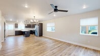 Located at 410 Pond Lily Dr in Bozeman, Montana, this contemporary two-story home offers a thoughtfully designed layout spread across two floors. The main level welcomes you with an open-concept living and kitchen area finished with warm light hardwood flooring and ceiling fans that enhance the bright, airy atmosphere. Large windows allow natural light to fill the space, creating a clean and inviting ambiance throughout.

The kitchen is a standout feature, showcasing rich dark shaker-style cabinetry, crisp white countertops, a central island ideal for prep and casual dining, and a full suite of stainless steel appliances including a gas range, microwave, and dishwasher. Pendant lighting above the island adds a modern touch.

The upper floor hosts three carpeted bedrooms, each featuring ceiling fans and generous windows that bring in natural light and neighborhood views. The primary bedroom offers a comfortable, well-proportioned retreat. Three full bathrooms are finished with dark vanity cabinetry, white countertops, and tile flooring. A dedicated laundry room with a full-size washer and dryer adds everyday convenience. Two hallways and closet storage ensure efficient use of space throughout this well-appointed Bozeman home.