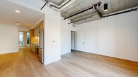 Located on Santa Monica Boulevard in the heart of West Los Angeles, this 2-bedroom, 1-bathroom unit offers a compelling blend of industrial-chic aesthetics and modern finishes. Light hardwood floors run throughout, complementing the striking exposed concrete ceilings with visible ductwork and piping that lend the space an urban, loft-like character. Large windows invite generous natural light and provide views of a landscaped courtyard, enhancing the open, airy feel of the living area. A glass-paneled entry door further brightens the space. The kitchen is outfitted with stainless steel appliances—including a refrigerator, range, microwave, and dishwasher—paired with light wood lower cabinetry, sleek white upper cabinets, and clean countertops. The spacious primary bedroom features exposed concrete ceiling details and connects to a well-appointed closet with built-in shelving and hanging rods. The second bedroom showcases a raw concrete accent wall with an exposed pipe, adding an artistic industrial touch. The bathroom includes a wood-toned vanity, white countertop, tall storage cabinet, and a lighted mirror. Throughout the unit, crisp white walls and consistent flooring create a cohesive, contemporary living environment.