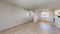 Located at 8911 Northeastern Blvd NE in Albuquerque, NM, this 2-bedroom, 3-bathroom single-floor unit offers a clean, modern aesthetic throughout. Light wood-look flooring flows consistently across all rooms, complemented by soft gray walls, white baseboards, and textured ceilings that lend a cohesive, updated feel.

The open living room is bright and spacious, drawing in natural light through large windows fitted with horizontal blinds. Ceiling fans with integrated lighting are found in both the living area and bedrooms, enhancing comfort and airflow. A pass-through opening connects the living room to the kitchen, creating an airy, connected layout.

The kitchen is well-appointed with two-tone cabinetry — white upper cabinets and gray lower cabinets — paired with white quartz-style countertops and a classic white subway tile backsplash. Black appliances, including a range and refrigerator, add a bold contrast.

The primary bedroom is generously sized, offering direct access to an en-suite bathroom featuring gray vanity cabinetry, a large mirror, and a walk-in closet with built-in shelving. Additional bathrooms include tub-shower combinations with white tile surrounds and windows for natural ventilation. Two closets provide ample storage throughout the unit.