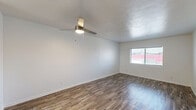 Located at 2408 E University Dr in Denton, TX, this single-story home offers five bedrooms and two full bathrooms across a well-organized floor plan. The combined kitchen and living room serves as the heart of the home, with the living area showcasing wood-look plank flooring, a textured ceiling, a ceiling fan with light, and a window that brings in natural light. The kitchen is thoughtfully updated with crisp white shaker-style cabinetry, granite-look countertops, a full suite of black appliances including a refrigerator, range, and dishwasher, and a window above the sink. The five bedrooms are comfortable and well-appointed, with ceiling fans in each room. Several bedrooms feature plush carpeting, while others continue the wood-look flooring, and each room includes windows for natural light. The two full bathrooms are clean and functional, each featuring a tub-shower combination with white tile surround, a single-sink vanity with white cabinetry, and wood-look flooring. A hallway connects the rooms throughout the home, providing a logical and efficient layout. The overall aesthetic is clean and neutral, with white walls and modern finishes throughout.