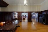 Located at 800 University Ave in Ithaca, NY, this distinguished two-floor historic building exudes classic architectural character throughout. The main floor centers on a dramatic hallway and grand staircase adorned with ornate dark wood paneling, a striking stained glass window, and pendant lantern lighting — creating a stately and welcoming entry. Warm hardwood floors flow through the living and dining areas, complemented by rich wainscoting and tall ceilings with crown molding that lend a sense of grandeur. The spacious living room features arched French doors and windows that flood the space with natural light, alongside a coffered ceiling, chandelier, and built-in seating with framed historical displays. A grandfather clock and antique furnishings add to the building's storied character. The upper floor is notably expansive, offering generous room sizes ideal for gatherings. The dining area features terracotta tile flooring, tile wainscoting, arched transom windows, pendant fixtures, and large French doors opening to the outdoors, providing ample seating capacity across multiple rooms. Throughout, the building maintains a cohesive aesthetic of dark hardwood millwork, leaded glass detailing, and refined architectural finishes that reflect its historic significance.
