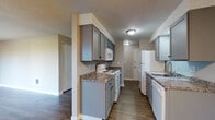 Located at 1904 East South Riverton Avenue in Spokane, WA, this single-floor unit offers a practical and comfortable layout with a clean, neutral aesthetic throughout. The galley-style kitchen is a standout feature, showcasing gray cabinetry with dark hardware, granite-look countertops, wood-look vinyl flooring, and white appliances including a range, over-the-range microwave, refrigerator, and dishwasher. Ample upper and lower cabinet storage lines both sides of the kitchen, providing generous workspace and organization. Adjacent to the kitchen, the open living and dining area is finished with durable wood-look flooring and features a ceiling fan. Large sliding glass doors flood the living space with natural light and offer direct views of a lush, tree-lined outdoor area. A dedicated walk-in closet provides additional storage convenience. The bedrooms are carpeted for comfort, each featuring baseboard heating and windows that bring in natural light. A textured ceiling is consistent throughout the unit, adding a classic residential touch. The bathroom includes a full-size soaking tub with a clean white surround. With its functional layout, updated finishes, and serene outdoor views, this Spokane unit offers a well-rounded living experience.