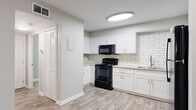 This well-appointed single-floor unit offers a thoughtfully designed layout that balances comfort and functionality. The open-concept living area flows seamlessly into the kitchen, creating an inviting and versatile space. Light wood-look flooring runs throughout the main living areas, complementing the neutral gray wall tones and crisp white baseboards that give the space a clean, contemporary aesthetic.

The kitchen is a standout feature, showcasing white shaker-style cabinetry, a classic white subway tile backsplash, and durable light-toned countertops. A full suite of black appliances — including a refrigerator, electric range, over-the-range microwave, and dishwasher — provides a bold contrast against the bright cabinetry. A double-door storage closet is conveniently located adjacent to the kitchen.

The bedrooms are generously proportioned, with each room benefiting from natural light through blinds-fitted windows that offer views of surrounding greenery. Select bedrooms feature soft wall-to-wall carpeting, while others continue the wood-look flooring for added versatility.

The bathroom is finished in a clean, modern style with wood-look flooring, a full tub-shower combination with tiled surround, a large vanity mirror with overhead lighting, and a white undermount sink with brushed nickel fixtures. Throughout the unit, the consistent use of neutral tones and modern finishes creates a cohesive and move-in ready environment.