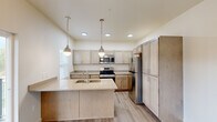 Located at 13809 E Carlisle Ave in Spokane Valley, WA, this well-appointed single-floor residence offers a thoughtfully designed layout with contemporary finishes throughout. The open-concept living area is anchored by light-toned luxury vinyl plank flooring that flows seamlessly from the entryway through the main living space, which features natural light from multiple windows and direct access to an outdoor balcony.

The kitchen is a standout feature, showcasing a large central island with an undermount sink, light wood cabinetry, quartz-style countertops, and a full suite of stainless steel appliances including a range, microwave, refrigerator, and dishwasher. Stylish pendant lights hang above the island, complementing the recessed ceiling lighting and creating a warm, inviting atmosphere.

The bedrooms are carpeted with a modern patterned carpet in neutral tones and offer generous wall space and natural light through multiple windows with views of the surrounding neighborhood. The bathroom features a clean, minimalist design with a full soaking tub, bright white surround, and coordinating luxury vinyl plank flooring. Throughout the residence, a cohesive neutral color palette and modern black hardware accents lend a fresh, contemporary feel.