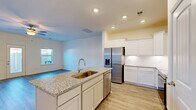 Located at 101 Alaina Avenue in Spring Hill, Tennessee, this well-appointed two-story home offers three bedrooms and three bathrooms across two thoughtfully designed floors. Light-toned hardwood-style flooring flows throughout, complementing the clean, neutral color palette and crisp white trim that define the home's modern aesthetic.

The main floor features an open-concept layout combining the living room, dining area, and kitchen into one connected space. The kitchen stands out with white shaker cabinets, granite countertops, a subway tile backsplash, a center island with an undermount sink, and a full suite of stainless steel appliances. The living room is bathed in natural light through multiple windows and includes a ceiling fan and direct access to the patio. A garage, entrance foyer, and hallway complete the ground level.

Upstairs, the spacious primary bedroom offers a tray ceiling with a ceiling fan, a walk-in closet, and an en-suite bathroom with a glass-enclosed shower. Two additional well-sized bedrooms feature natural light and ample closet space. A dedicated laundry area with a side-by-side washer and dryer adds everyday convenience. With five closets, two staircases, and three full bathrooms, this home delivers practical comfort in a clean, move-in-ready package.
