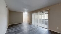 This single-floor unit presents a clean, updated interior with wood-style laminate flooring installed consistently throughout the living spaces, bedroom areas, and bathroom. The living room serves as the central gathering space, distinguished by a full-width sliding glass door fitted with vertical blinds that allow adjustable natural light and provide views to the outdoors. The textured ceiling adds a classic architectural detail visible across the main living areas.

An adjoining dining area connects seamlessly to the living room, maintaining an open, flowing layout between the two spaces. The kitchen is efficiently arranged, featuring stainless steel appliances including a range, microwave, and dishwasher, complemented by dark countertops and white cabinetry.

The bedroom offers a well-proportioned, quiet space with a window dressed in horizontal blinds, providing natural light and ventilation. The bathroom has been updated with a dark-finished vanity cabinet, integrated white sink basin, brushed nickel hardware, and a mirror. A separate water closet area provides added privacy. Neutral wall tones and clean finishes throughout contribute to a cohesive, move-in-ready aesthetic.