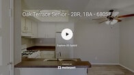 This single-floor residence offers a practical and functional layout across two bedrooms, one kitchen, a hallway, and a dedicated closet. The open-concept kitchen serves as a central feature of the living area, equipped with white cabinetry, dark countertops, a gas range, a full-size refrigerator, and a double-basin sink integrated into a peninsula breakfast bar that separates the kitchen from the living space. A raised tray ceiling with a flush-mount light fixture adds architectural interest to the kitchen area, while light wood-style flooring extends through the main living and kitchen zones. A ceiling fan with a light kit is positioned in the living area, contributing to airflow and functionality.

Both bedrooms are carpeted and receive natural light through horizontal windows fitted with vertical blinds. The primary bedroom features full-width mirrored sliding closet doors, enhancing the sense of space. The secondary bedroom is more compact, offering a quiet, neutral retreat. A dedicated walk-in closet provides built-in shelving along the walls, maximizing storage capacity. Neutral-toned walls and textured ceilings are consistent throughout, creating a cohesive, understated aesthetic across the entire unit.