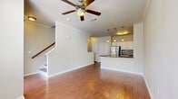 This three-story townhome at 250 Treeline Park in San Antonio, Texas offers a well-organized layout spread across three distinct levels. The ground floor provides an attached garage with an automatic opener, offering direct interior access via a staircase leading to the main living areas above.

The main living level features warm hardwood flooring throughout, crown molding, and ceiling fans that enhance the bright, airy atmosphere. The open-concept living area connects seamlessly to a well-appointed kitchen, which boasts stainless steel appliances, dark granite countertops, a curved breakfast bar peninsula, white cabinetry, and a patterned tile backsplash with pendant lighting overhead. A sliding glass door opens onto a private balcony, extending the living space outdoors and allowing natural light to fill the room.

The upper floor is home to the spacious primary bedroom, finished with plush carpet, a ceiling fan, and a large window that invites natural light. Multiple closets provide generous storage throughout. The full bathroom features dark granite countertops, white cabinetry, hardwood-style flooring, and a tiled shower-tub combination. Additional conveniences include a dedicated laundry area and a pantry, making this a functional and comfortable multi-level home.