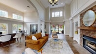 Located at 3901 Rapid Run Dr in Lexington, Kentucky, this single-story clubhouse is a standout example of refined community architecture. The space is defined by its dramatic vaulted ceilings that soar overhead, creating an expansive, airy atmosphere throughout the main gathering area. Tall, multi-pane clerestory windows flood the interior with abundant natural light, enhancing the open and welcoming ambiance.

The grand entry foyer welcomes visitors with rich hardwood-style flooring, decorative wainscoting, and stately white columns that frame the space with classical elegance. A checkered entry mat and double glass doors provide a polished first impression.

The main lounge area serves as the heart of the clubhouse, anchored by a striking floor-to-ceiling stone fireplace flanked by built-in shelving. Architectural arches and fluted columns divide the space gracefully, while a dedicated dining area sits just beyond. Large sliding glass doors open directly to an outdoor pool and patio area, seamlessly connecting the interior to the exterior.

Throughout the space, crisp white millwork, recessed lighting, and a decorative chandelier contribute to a sophisticated yet inviting character. The cohesive design blends traditional architectural details with a bright, modern palette, making this clubhouse a functional and visually impressive community gathering destination.