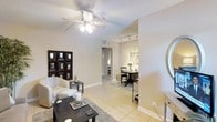 This single-floor residence offers a thoughtfully designed open layout that seamlessly connects the living and dining areas, creating a cohesive and functional living environment. The living area is finished with light-toned ceramic tile flooring that extends throughout the space, contributing to a clean, airy aesthetic. A ceiling fan with an integrated light fixture anchors the living room, providing both comfort and illumination. Neutral wall tones complement the space and allow for versatile décor options.

The dining area is set apart by track lighting mounted on the ceiling, which highlights the space with a warm, directed glow. A corridor leads toward additional rooms, offering a sense of depth and privacy within the layout. The transition between spaces is smooth and well-proportioned, making the floor plan feel open yet organized.

Architectural details such as clean baseboards, defined room separations, and consistent flooring throughout tie the interior together cohesively. The overall ambiance is calm and neutral, with a modern yet approachable character that suits a variety of lifestyles. The space is well-lit by a combination of natural and artificial light, enhancing the bright and welcoming atmosphere throughout.
