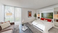 Located at 449 East Arenas Road in the heart of Palm Springs, California, this efficiently designed single-floor unit offers a smart, open layout that maximizes every inch of available space. The main living area seamlessly combines sleeping and lounging functions, anchored by a built-in Murphy bed with integrated shelving — a clever space-saving feature that adds both functionality and visual interest. White-painted brick walls lend a clean, textural backdrop throughout, while large floor-to-ceiling sliding glass doors with vertical blinds flood the space with natural light and provide views of the lush outdoor greenery beyond.

The kitchen is well-appointed with warm wood cabinetry on the lower cabinets, white upper cabinetry, stainless steel appliances including a full-size refrigerator, electric range, and microwave, along with light tile flooring that continues throughout the unit. The open-plan design ensures the kitchen flows naturally into the main living space.

The bathroom is thoughtfully finished with large-format light tile flooring, a warm wood vanity with an integrated sink, and a glass-enclosed walk-in shower featuring marble-style tile surround. A decorative patterned accent mat adds a touch of personality. A dedicated closet completes this practical and stylish Palm Springs retreat.