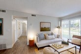 Located at 7845 Allison Way in Arvada, Colorado, this thoughtfully designed 2-bedroom, 2-bathroom residence offers a comfortable and functional single-floor layout. Wood-style flooring flows throughout the main living areas, creating a cohesive and warm aesthetic. The living room serves as the heart of the home, highlighted by a classic fireplace with a chevron-patterned screen, neutral walls, a textured ceiling, and a sliding glass door that invites natural light and outdoor views. The kitchen is well-appointed with stainless steel appliances — including a refrigerator, range, and dishwasher — paired with white cabinetry, gray countertops, and a skylight that brightens the space. Both bathrooms are cleanly finished, featuring tub-shower combinations, wood-look tile flooring, and built-in shelving for convenient storage. The primary bedroom offers a comfortable, carpeted retreat with natural light filtering through curtained windows. The secondary bedroom is equally well-sized with soft carpet and a neutral palette. Additional features include an in-unit laundry area, a dedicated closet, and a dining space adjacent to the kitchen and living room. The overall ambiance is bright, clean, and move-in ready.