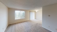 Located at 13011 Meridian E in Puyallup, Washington, Unit 208 is a single-floor residence featuring a practical and comfortable layout. The living area is generously proportioned, with plush carpeting underfoot, neutral walls, and two windows — including a large picture window and a sliding glass door with vertical blinds — that invite natural light and frame views of surrounding greenery.

The bedrooms are carpeted and well-sized, each featuring windows with blinds that provide outdoor views and natural light. At least one bedroom includes access to a walk-in closet with built-in shelving, offering ample storage. Textured ceilings are consistent throughout the unit, contributing to a classic residential aesthetic.

The kitchen is efficiently designed with light wood cabinetry, granite-look laminate countertops, a stainless steel sink, and a dishwasher — providing practical functionality for everyday use.

The bathroom is clean and straightforward, featuring tile flooring, a full tub-shower combination, a toilet, and a vanity with a wood cabinet base and speckled countertop.

Overall, the unit presents a neutral, move-in-ready interior with consistent finishes, natural light across multiple rooms, and a functional floor plan suited for comfortable everyday living.